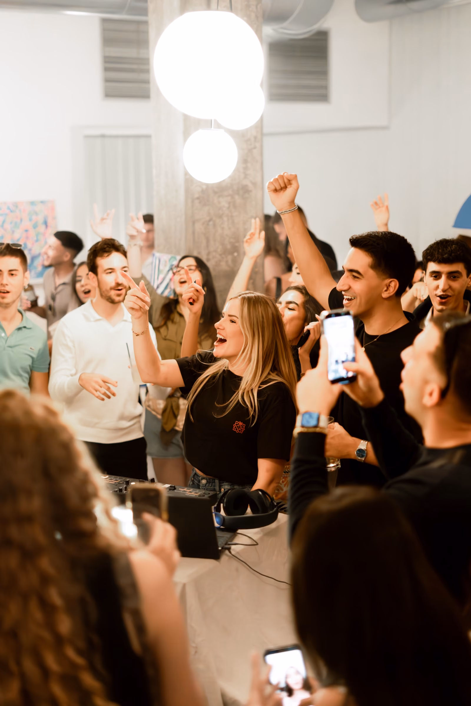 A daytime Coffee Party in a white room, Lisa behind the decks with the crowd