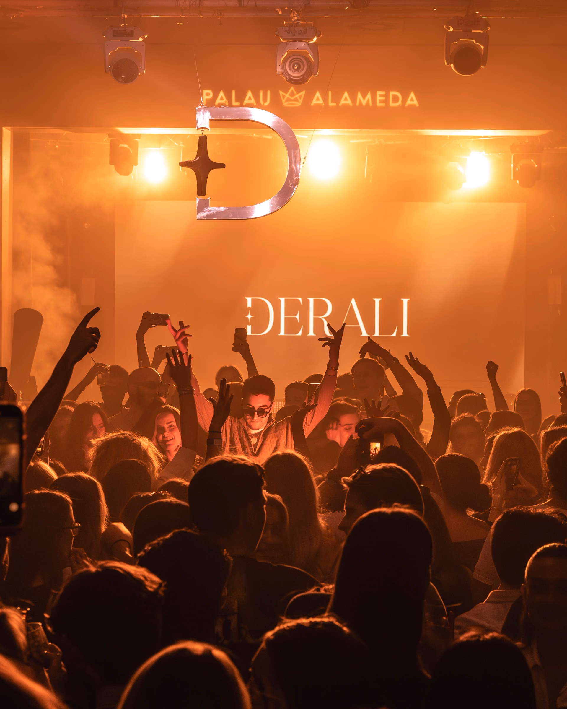 The Derali monogram projected above a packed space at Palau Alameda