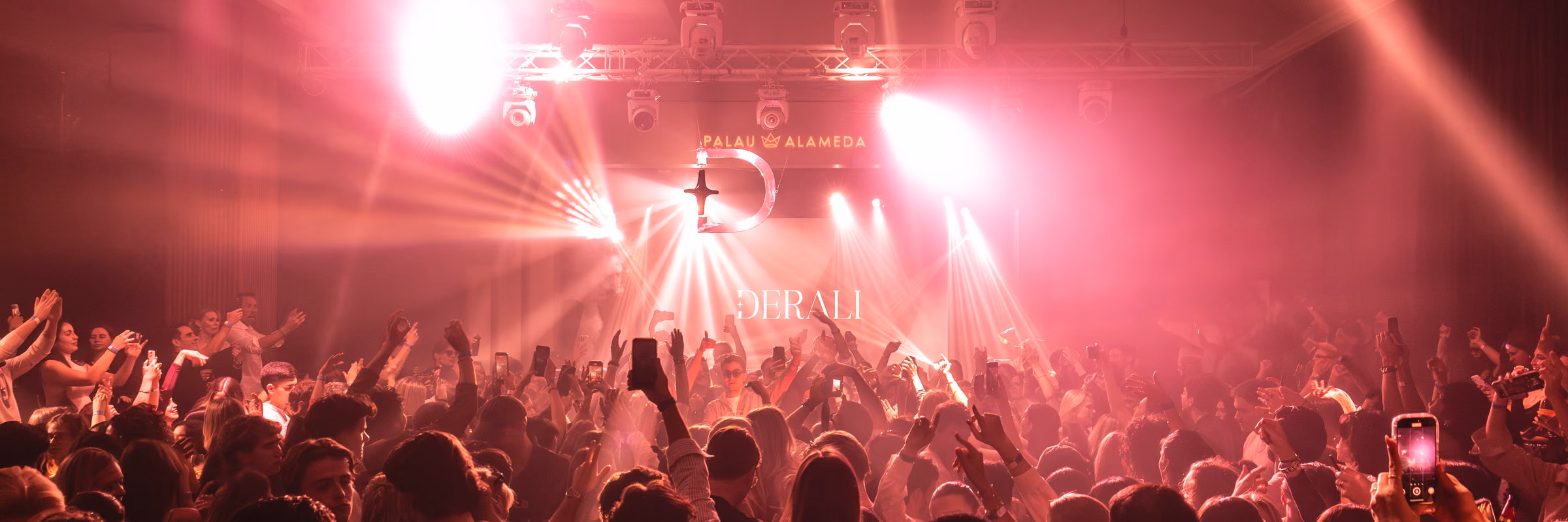 Magenta beams over a full space at Palau Alameda, the Derali wordmark lit behind the booth