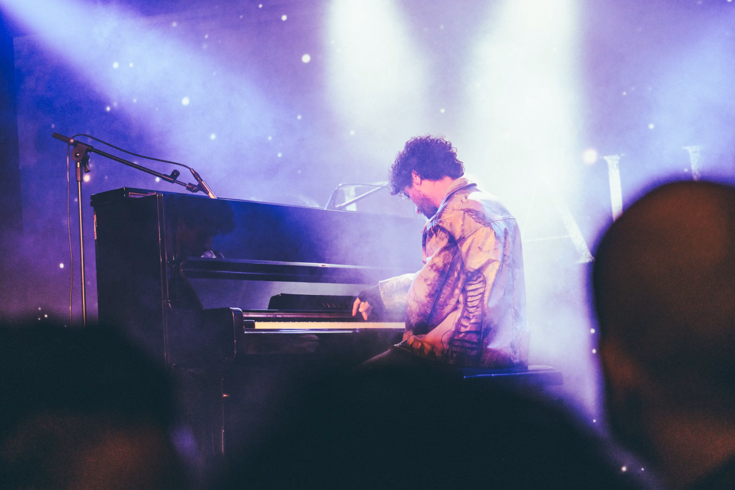 A pianist at a grand piano in blue and violet stage light, the Derali wordmark behind