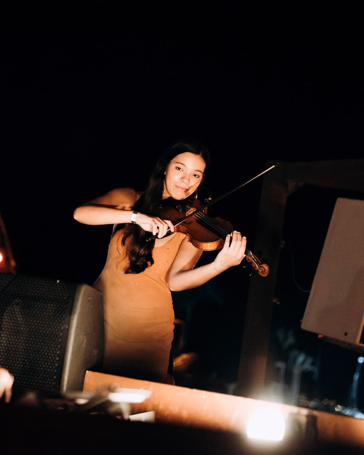 A violinist in a tan dress playing beside the booth, Yassine at the decks in the foreground