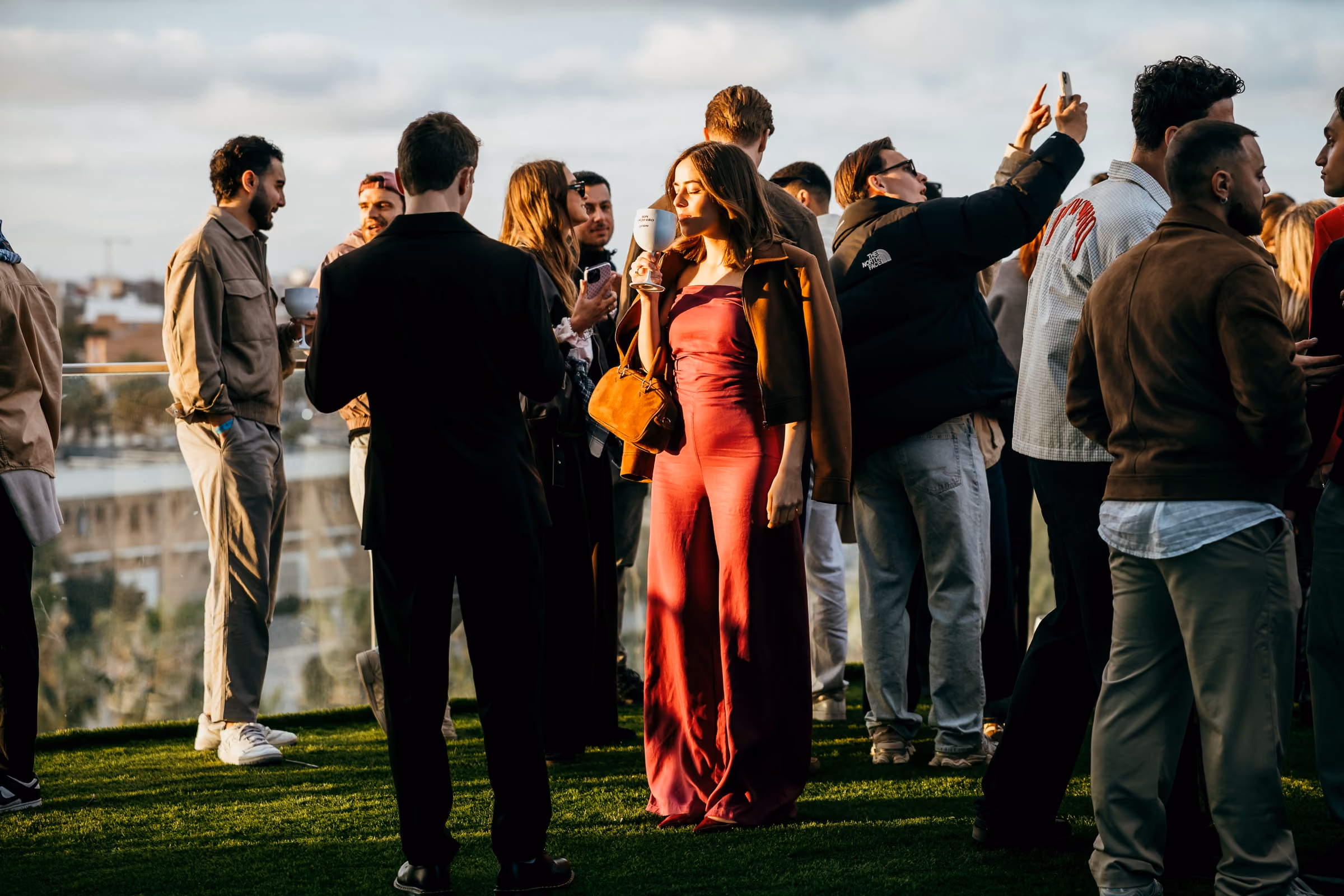 People on the rooftop at Veles e Vents in low golden sun, the port behind them